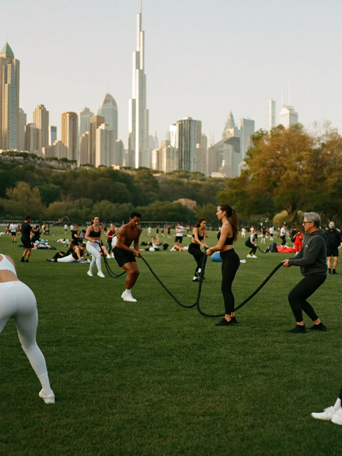 An outdoor HIIT circuit class training on a green park lawn in the evening
