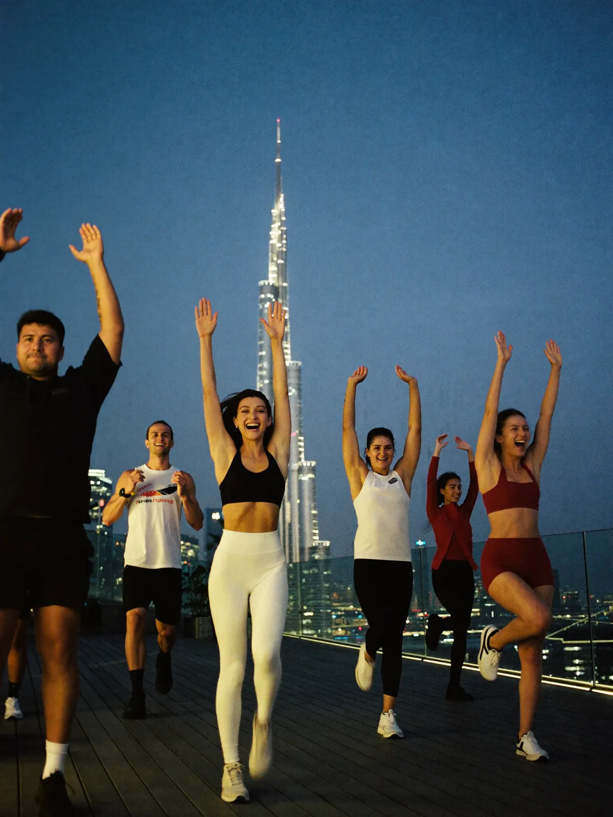 A high-intensity training class mid jump on a rooftop terrace at dusk