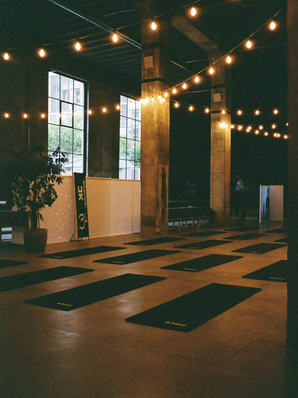 An industrial-chic indoor event space with mats arranged for a class