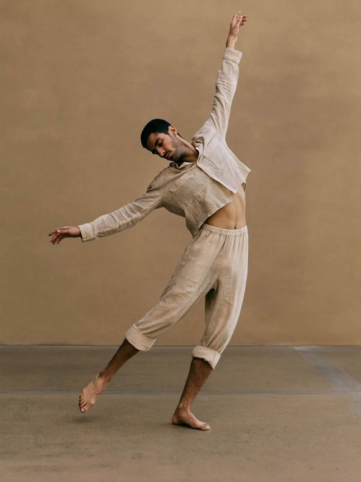 A dancer mid-turn with flowing fabric against a pale seamless backdrop
