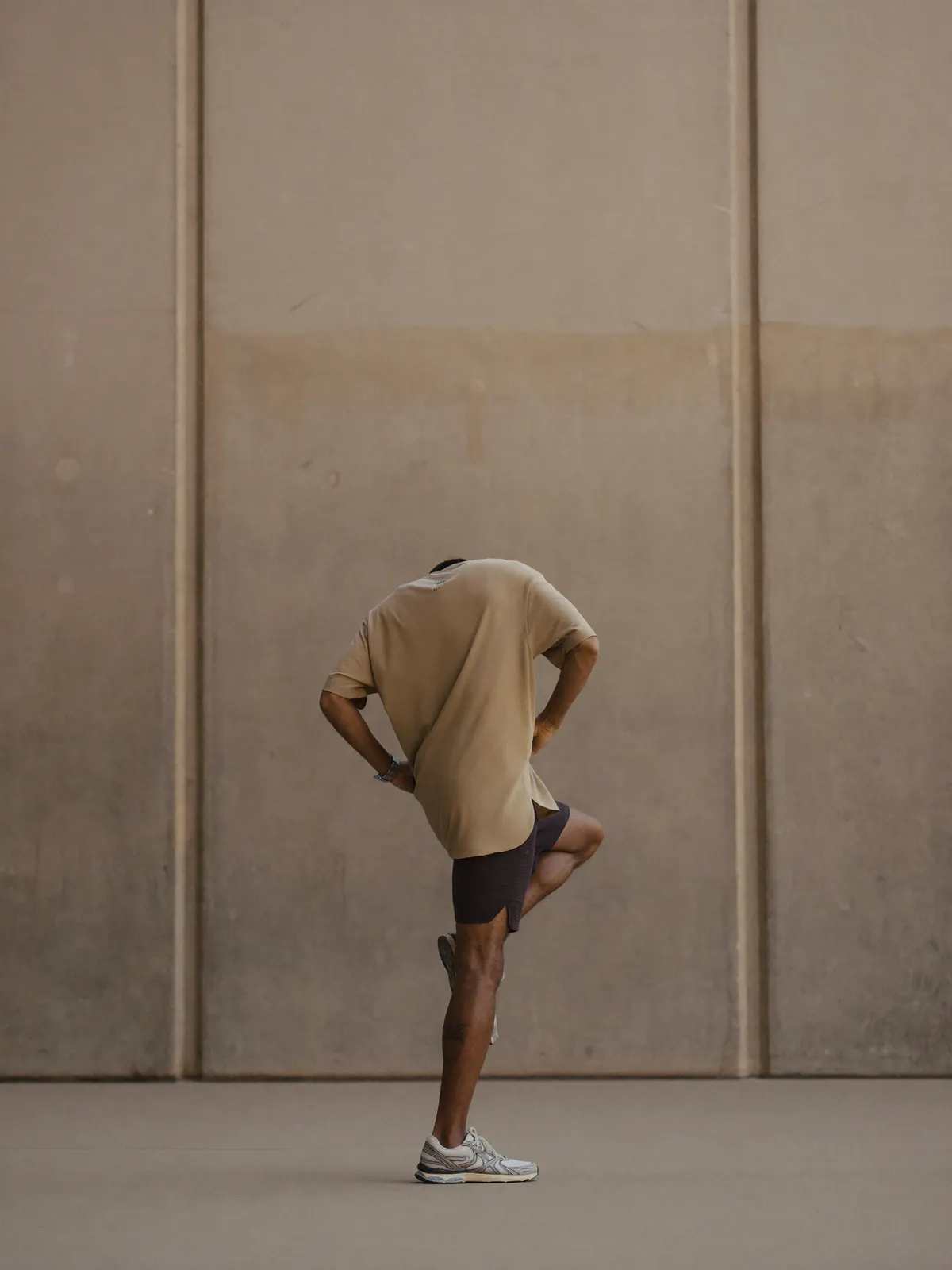 An athlete frozen mid jump-rope skip against a plain warm concrete wall